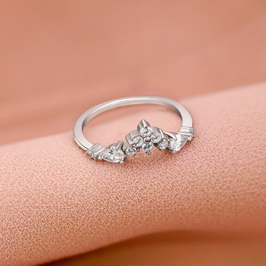 A floral design silver ring with sparkling diamonds on a pink background